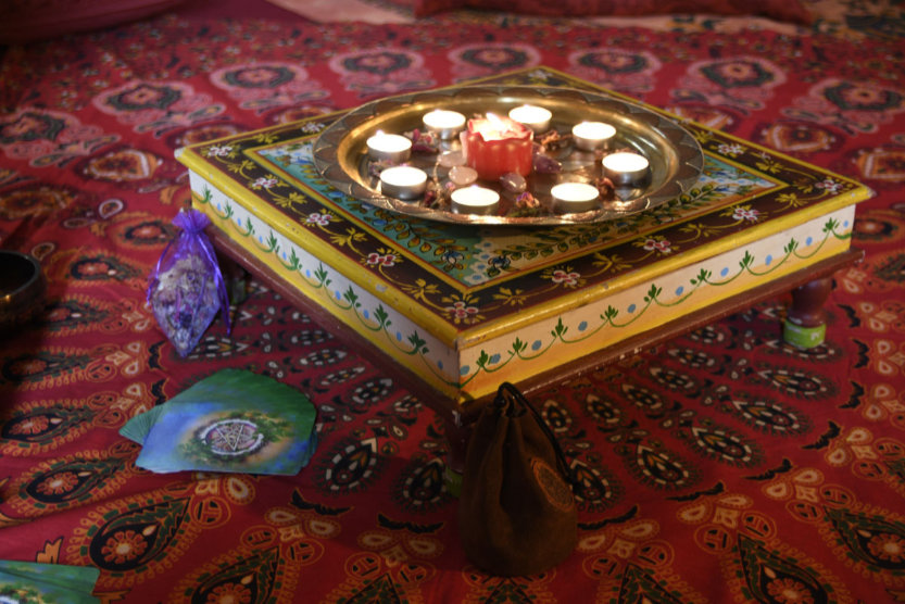 A small table with an arragenment of candles and crystals